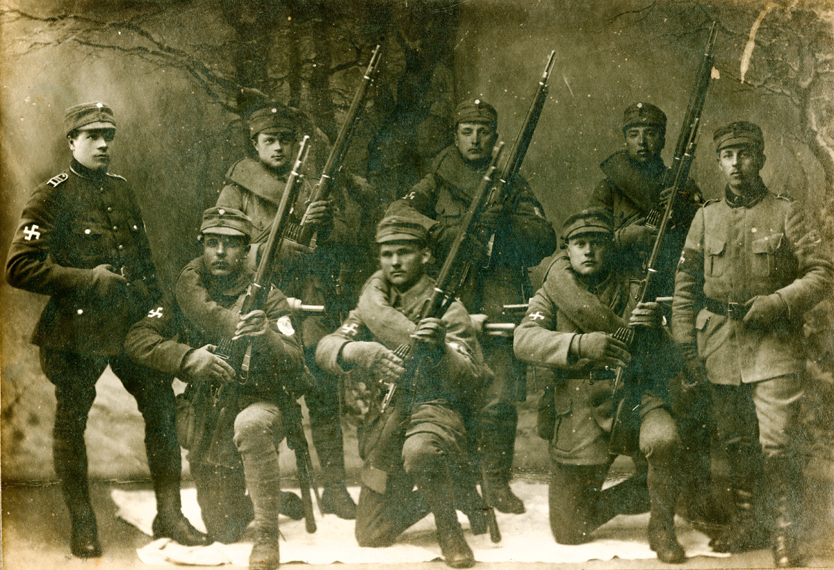 ???resource.thumbnail???: Ateljéfotografi av åtta militärklädda män varav ...
	
		Ateljéfotografi av åtta militärklädda män varav sex poserar med vapen. Alla bär bindel runt högra...